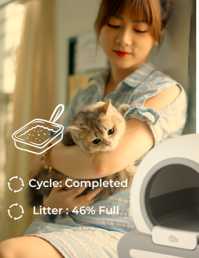 Woman holding a cat next to an open litter box with a completed cycle indicator.