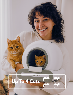 Woman holding a white pet carrier with two cats inside, smiling at the camera.