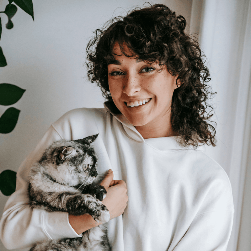 Woman holding a cat and smiling in a home setting